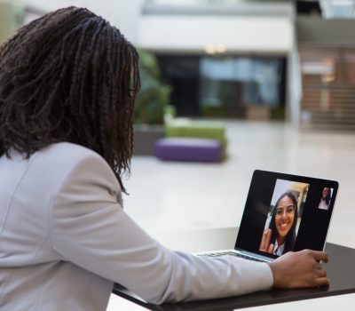 une jeune femme devant son ordinateur en visioconférence